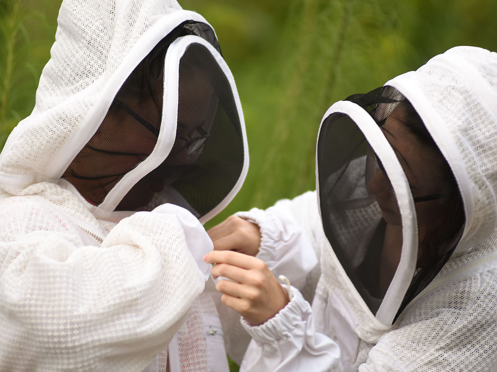 Danielle Gafford helps Jenna Moeller put on a beehive suit